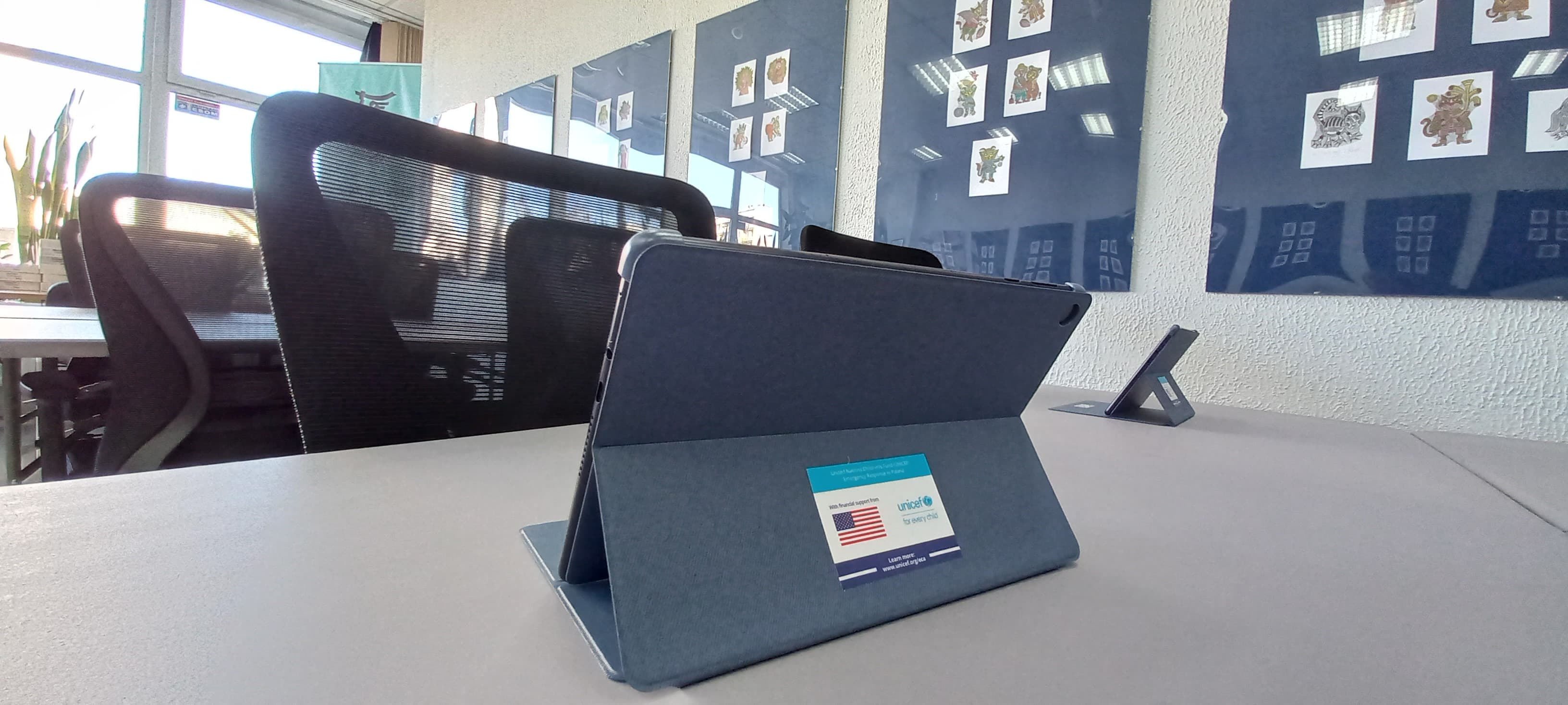 Sala biblioteczna. Tablet z naklejką z logo Fundacji Unicef.